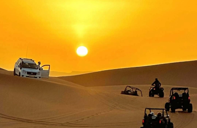 Dune buggy parked on sand dune at sunrise in Merzouga