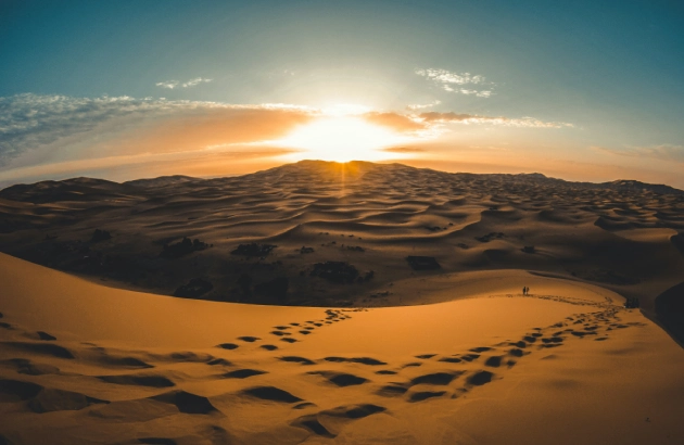 Sunrise Merzouga camel ride with golden light illuminating the dunes