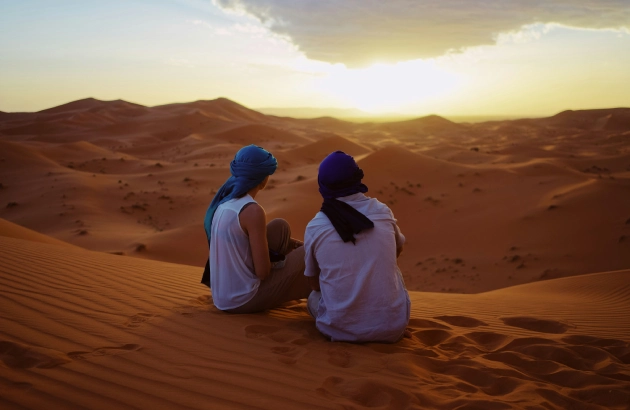 Happy travelers enjoying sunset views at Erg Chebbi dunes during Errachidia to Merzouga tour
