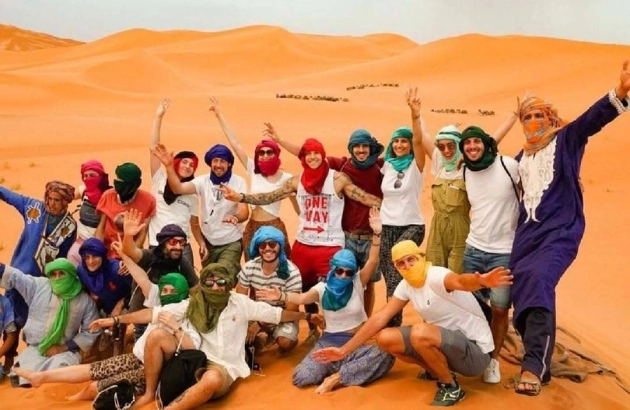 Group of happy tourists with guide on Errachidia to Merzouga desert tour