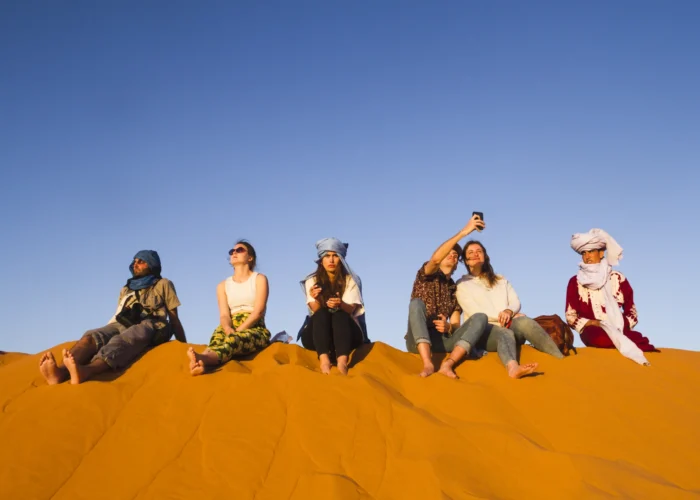 Panoramic view of orange sand dunes and a dromedary caravan during a 3 days desert tour from Agadir.