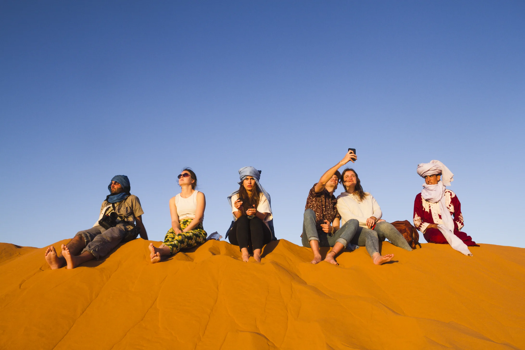 Panoramic view of orange sand dunes and a dromedary caravan during a 3 days desert tour from Agadir.