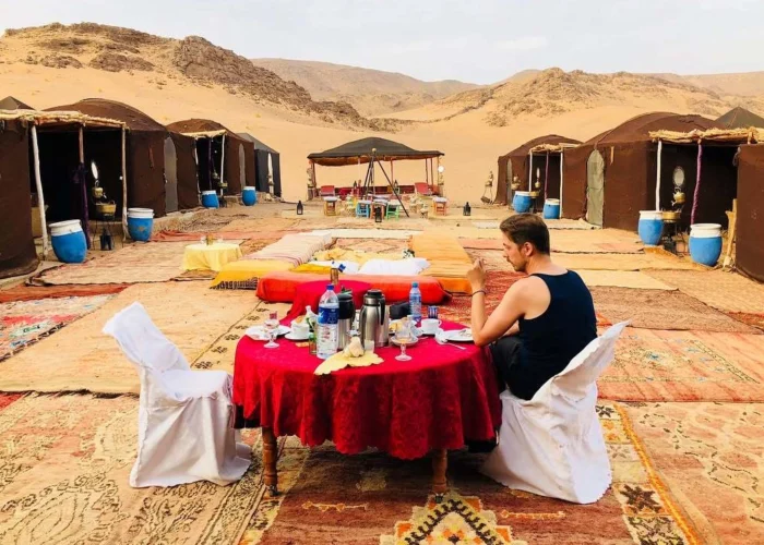 Traveler enjoying a traditional Moroccan dinner at a desert camp in Zagora during a 2-day Sahara tour from Marrakech