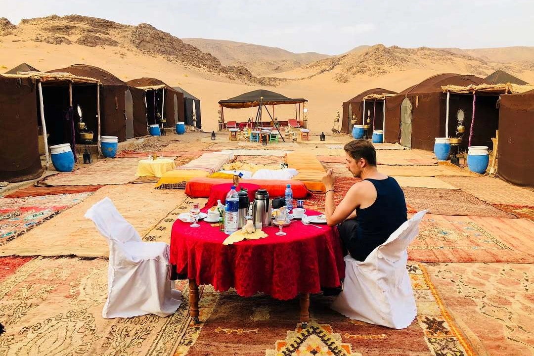 Traveler enjoying a traditional Moroccan dinner at a desert camp in Zagora during a 2-day Sahara tour from Marrakech
